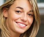Close-up of a smiling blonde woman looking at the camera.